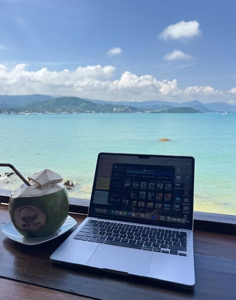 Laptop und Kokosnuss auf einem Tisch mit Meerblick